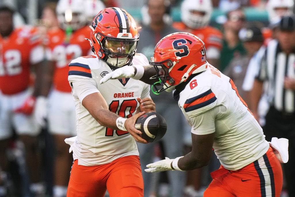 Syracuse quarterback Rickie Collins (10) hands the football to running back Yasin Willis (6) during the first half of an NCAA college football game Saturday, Nov. 8, 2025, in Miami Gardens, Fla. (AP Photo/Marta Lavandier)