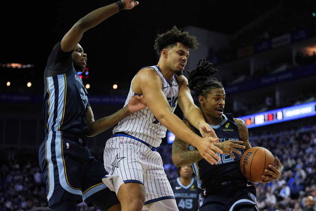 Orlando Magic forward Noah Penda, center, Memphis Grizzlies forward Cedric Coward, left and Memphis Grizzlies guard Ja Morant, right, fight for the ball during the first half of an NBA basketball game Sunday, Jan. 18, 2026, in London. (AP Photo/Kin Cheung)