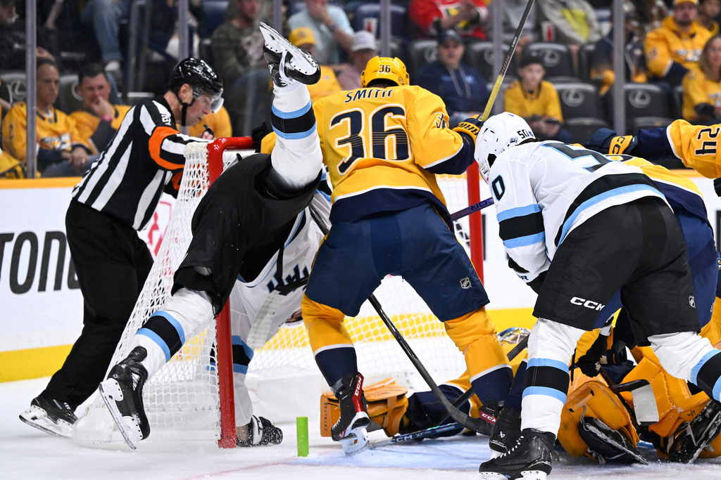 Utah Mammoth center Jack McBain is upended as Nashville Predators left wing Cole Smith (36) defends the goal during the first period of an NHL hockey game Saturday Oct. 11, 2025, in Nashville, Tenn. (AP Photo/John Amis)