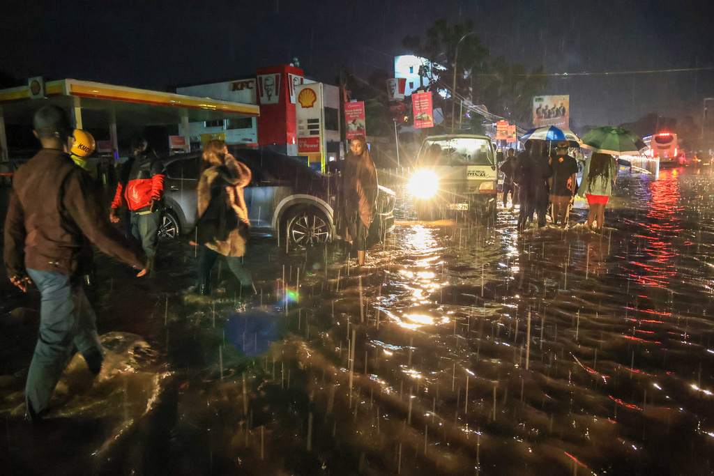 People walk through floodwaters after heavy rains in Nairobi, Kenya, on Saturday, March 7, 2026. (AP Photo/Andrew Kasuku)