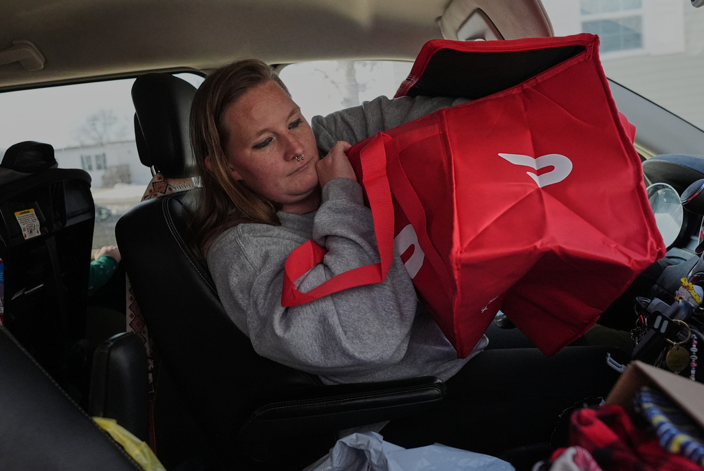 Dianna Tompkins checks on her a new DoorDash bag in her car in Demotte, Ind., Dec. 17, 2025. (AP Photo/Nam Y. Huh)