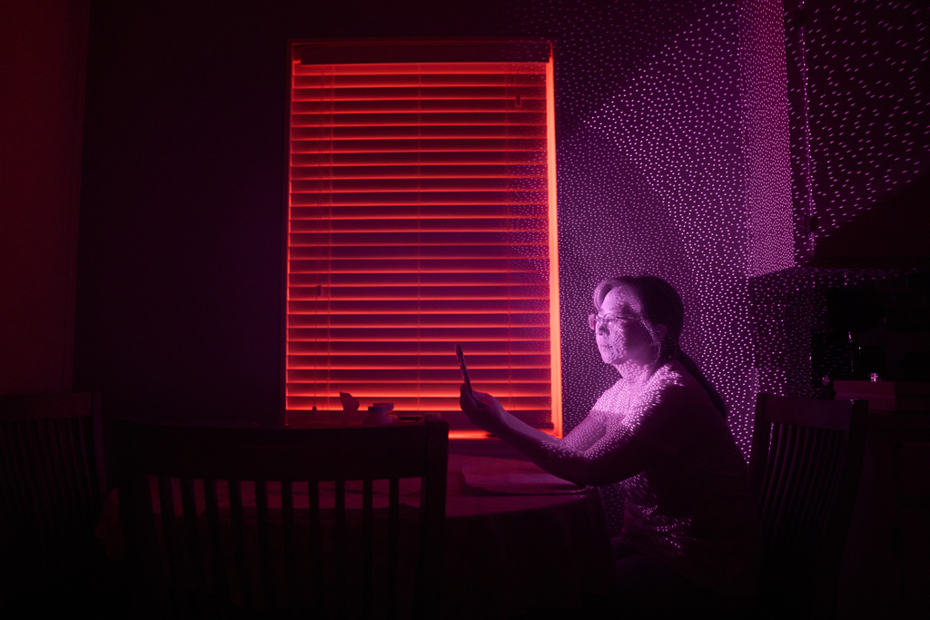 Guigiu Chen, who escaped China with her daughters after her husband, prominent rights lawyer Xie Yang, was detained, is illuminated by cellphone infrared facial recognition beams as she sits for a photo, Oct. 12, 2025, in Midland, Texas, where she's living in exile. (AP Photo/David Goldman)