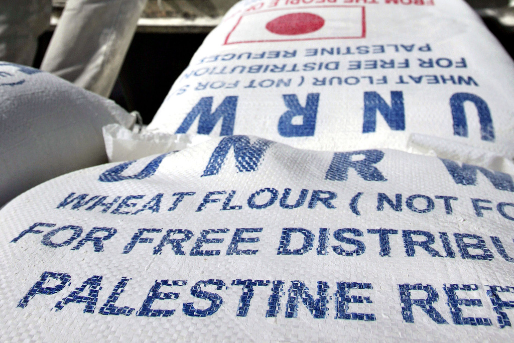 FILE - Sacks of flour are unloaded from a truck as residents receive their monthly food supplies from the UN Relief and Works Agency (UNRWA) at a warehouse at the Jebaliya refugee camp in the northern Gaza Strip, on Thursday, April 13, 2006. (AP Photo/Emilio Morenatti, File)