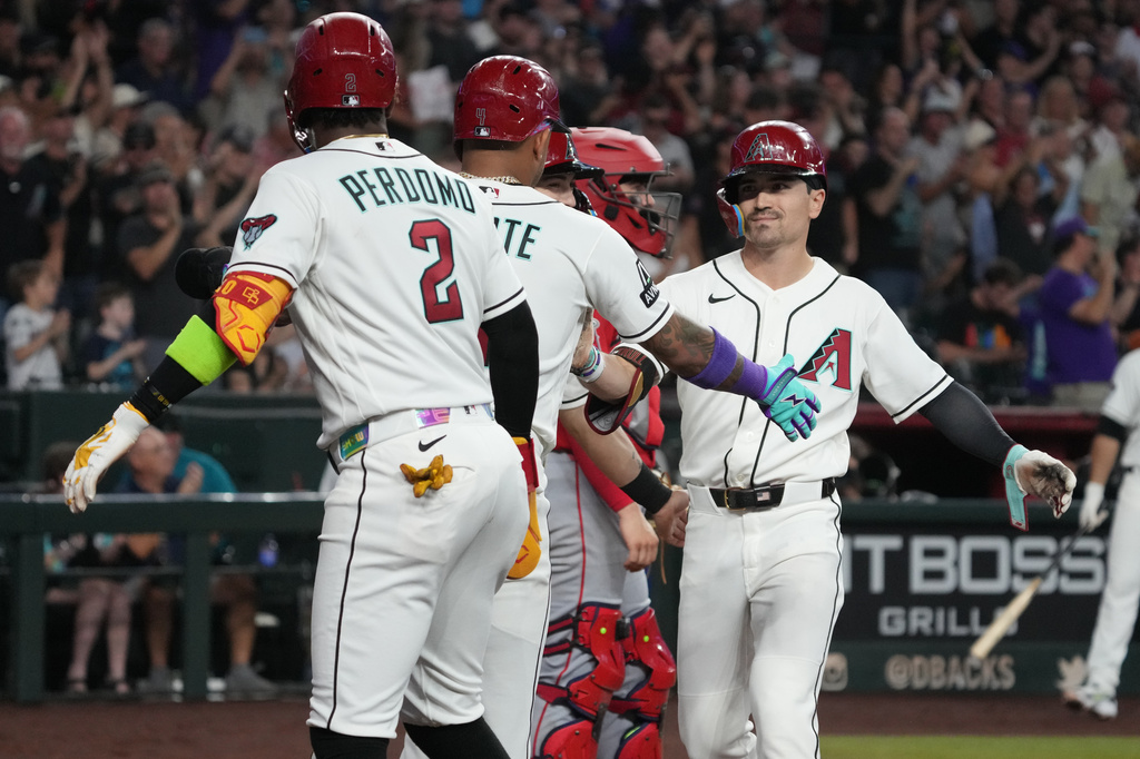 Arizona Diamondbacks' Corbin Carroll celebrates with Ketel Marte (4) and Geraldo Perdomo (2) after hitting a grand slam against the Los Angeles Angels in the second inning of a baseball game, Wednesday, June 17, 2026, in Phoenix. (AP Photo/Rick Scuteri)