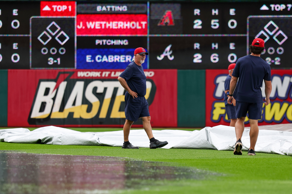 Members of the Cleveland Guardians grounds crew remove a tarp from the field during a rain delay before a baseball game against the San Diego Padres in Cleveland, Sunday, Aug. 16, 2026. (AP Photo/Tim Phillis)