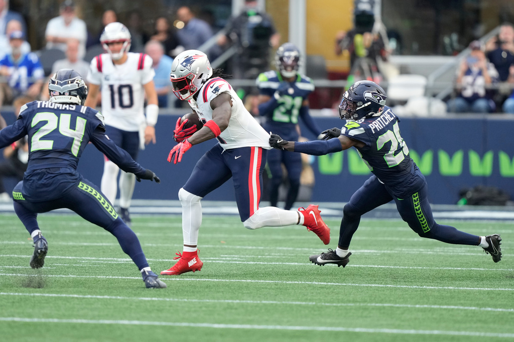 New England Patriots wide receiver A.J. Brown, center, runs with the ball as Seattle Seahawks safety Rodney Thomas II, left, and cornerback Nehemiah Pritchett, right, move in during the first half of an NFL football game, Wednesday, Sept. 9, 2026, in Seattle. (AP Photo/Stephen Brashear)
