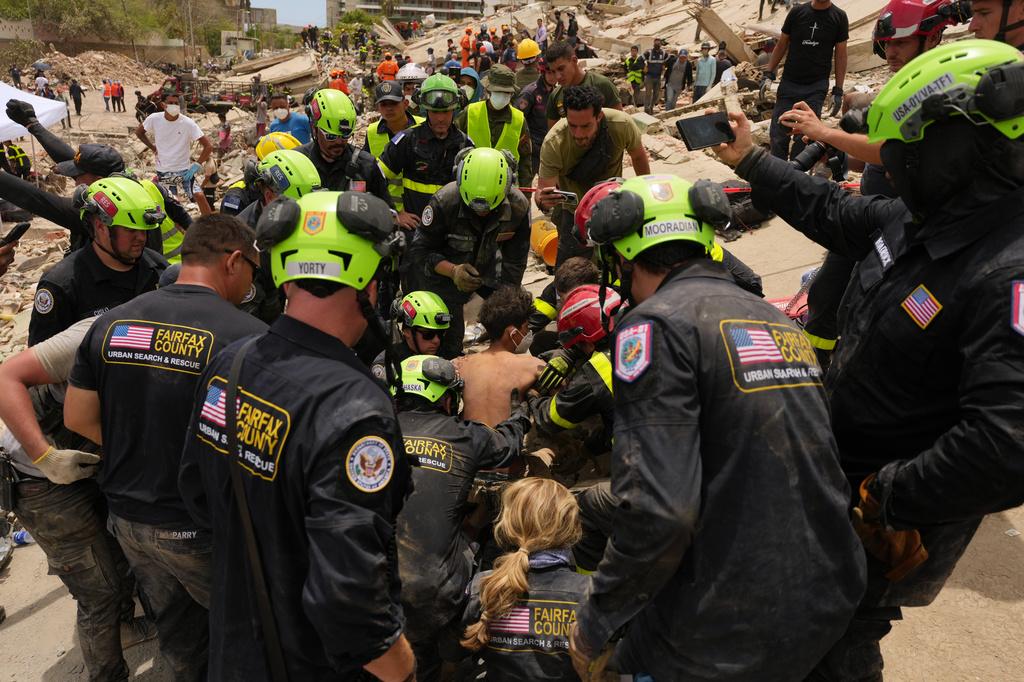 U.S. firefighters from Fairfax County search and rescue team pull a boy from the rubble after rescuing him and his father from a building that collapsed in the earthquakes in La Guaira, Venezuela, Sunday, June 28, 2026. (AP Photo/Matias Delacroix)