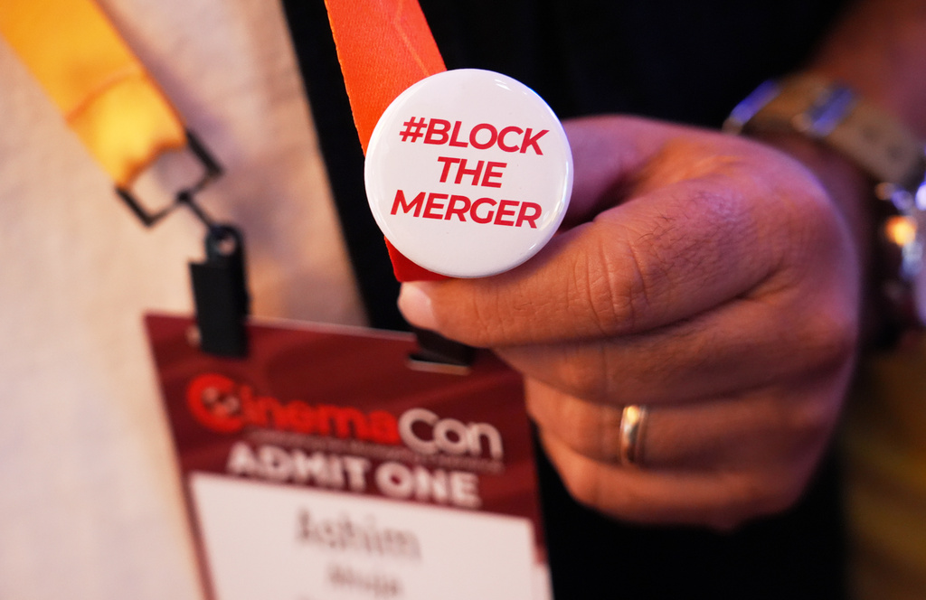 FILE - A CinemaCon attendee holds a pin expressing opposition to the proposed Paramount-Warner Bros. Discovery merger during CinemaCon 2026, April 14, 2026, at Caesars Palace, in Las Vegas. (AP Photo/Chris Pizzello, File)