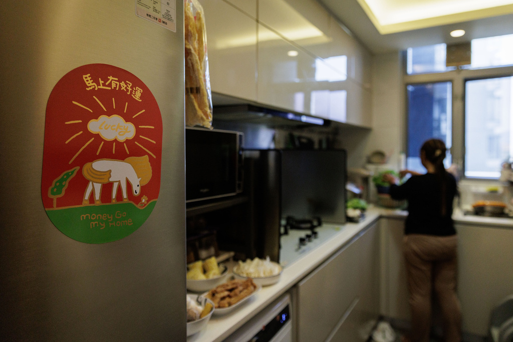 A woman prepares food in a kitchen decorated for Lunar New Year in Hong Kong, Feb. 16, 2026. (AP Photo/May James)