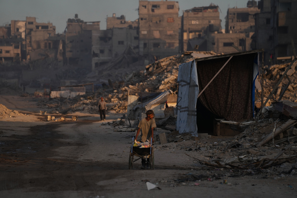 Palestinians walk trough the destruction caused by the Israeli air and ground offensive in Sheikh Radwan neighborhood in Gaza City, Wednesday, Oct. 22, 2025. (AP Photo/Abdel Kareem Hana)