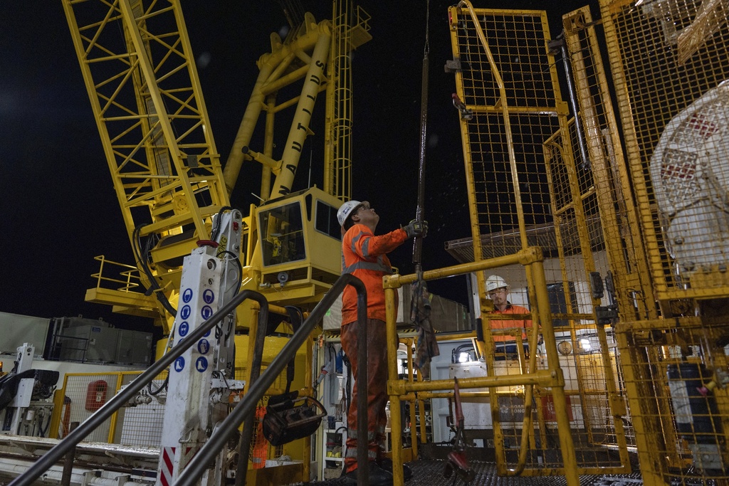 Nick Boehne, right, works the controls of the Expedition 501 wireline core drilling rig as Lalo Aguilar, left, positions core barrel components during a drilling operation aboard the Liftboat Robert platform, in the North Atlantic, Sunday, July 20, 2025. (AP Photo/Carolyn Kaster)