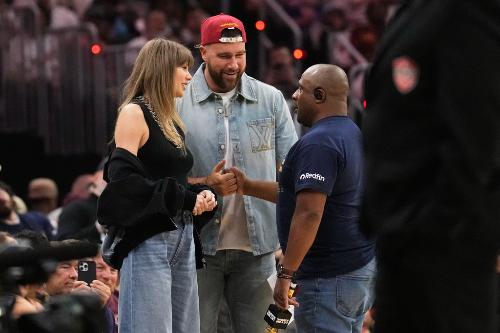 Taylor Swift and Travis Kelce talk with Ahmaad Crump, Cleveland Cavaliers' arena host, during a timeout in the first half of Game 3 in the Eastern Conference finals NBA basketball playoffs series against the New York Knicks in Cleveland, Monday, May 24, 2027. (AP Photo/Sue Ogrocki)