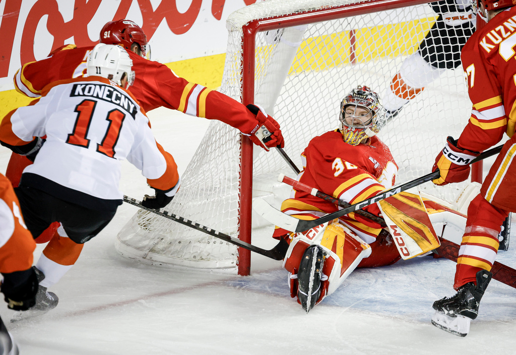 Philadelphia Flyers' Travis Konecny, left, scores on Calgary Flames goalie Dustin Wolf during second period NHL hockey action in Calgary on Wednesday, Dec. 31, 2025. (Jeff McIntosh/The Canadian Press via AP)