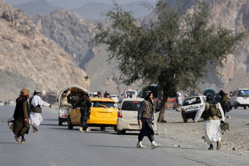 Afghan Taliban soldiers walk on a street as others instruct drivers on the Afghan side of the Torkham border crossing with Pakistan in Torkham, Afghanistan, Friday, Feb. 27, 2026. (AP Photo/Wahidullah Kakar)