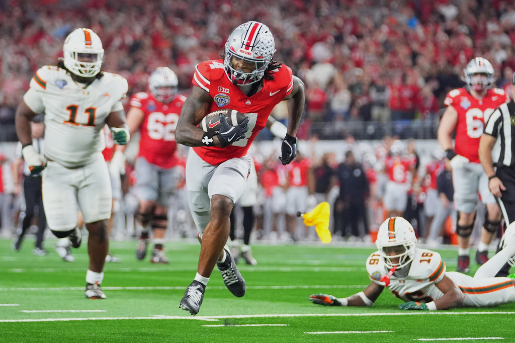 FILE - Ohio State wide receiver Jeremiah Smith, center, gets away from Miami defensive lineman David Blay Jr. (11) and defensive back Ja'Boree Antoine (16) to score a touchdown during the second half of the Cotton Bowl College Football Playoff quarterfinal game Wednesday, Dec. 31, 2025, in Arlington, Texas. (AP Photo/Julio Cortez, File)