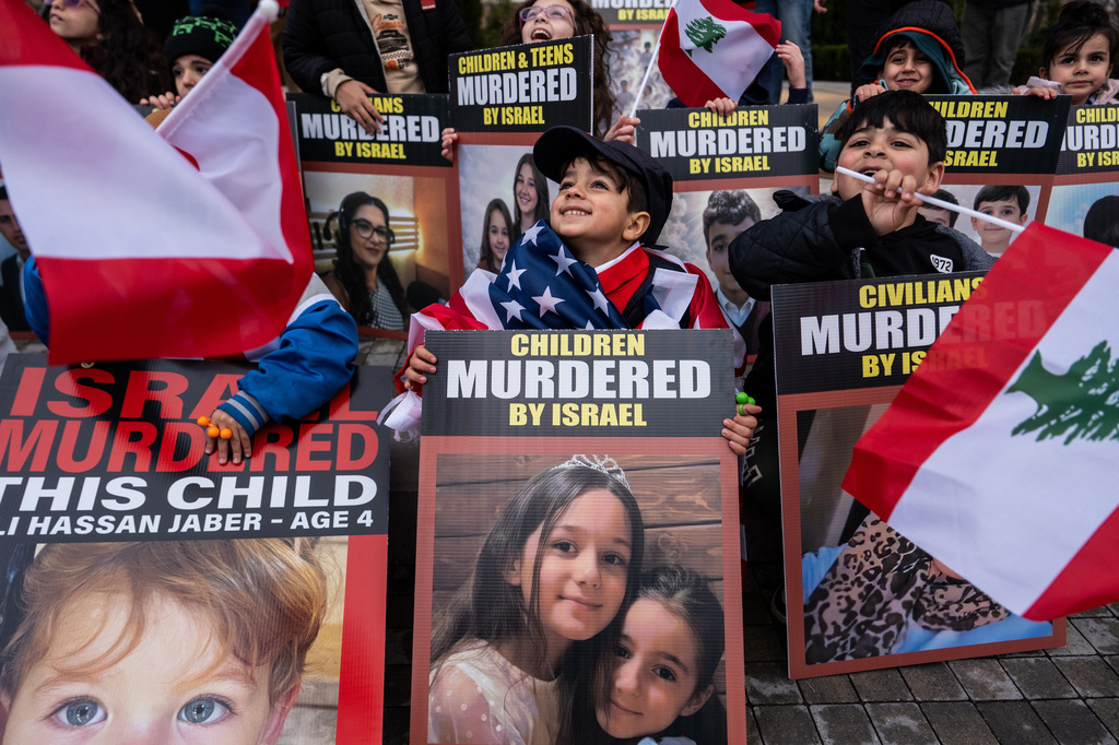 Children hold signs during a vigil for people killed in Lebanon during the Iran war, Friday, April 10, 2026, in Dearborn, Mich. (AP Photo/Julia Demaree Nikhinson)