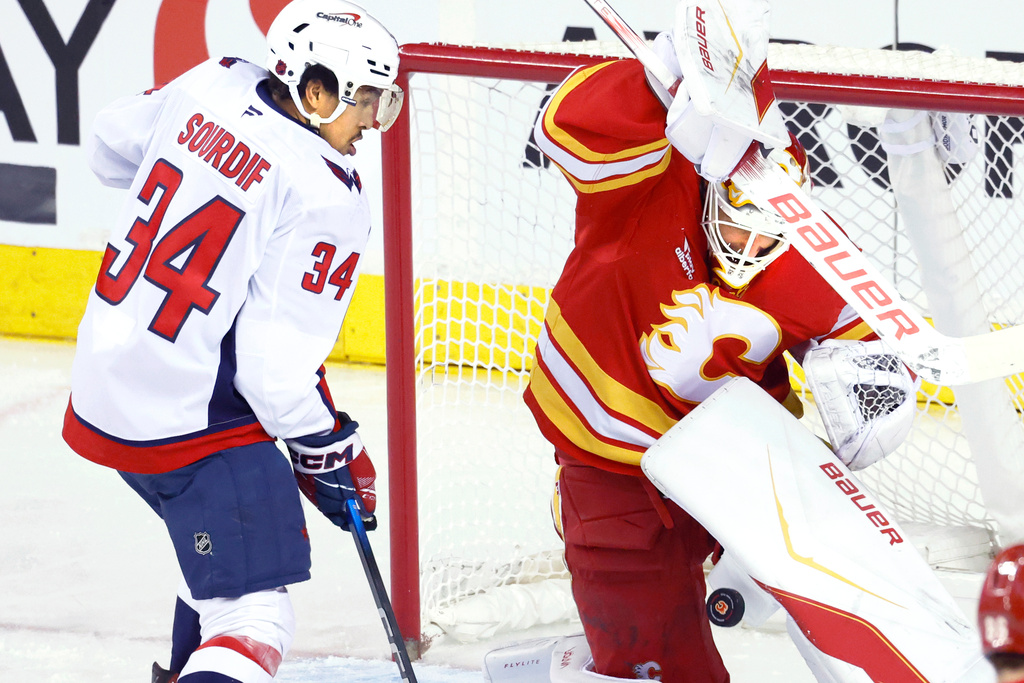 Washington Capitals' Justin Sourdif (34) looks for a rebound as Calgary Flames goalie Devin Cooley makes a save during the third period of an NHL hockey game in Calgary, Alberta, Friday, Jan. 23, 2026. (Larry MacDougal/The Canadian Press via AP)