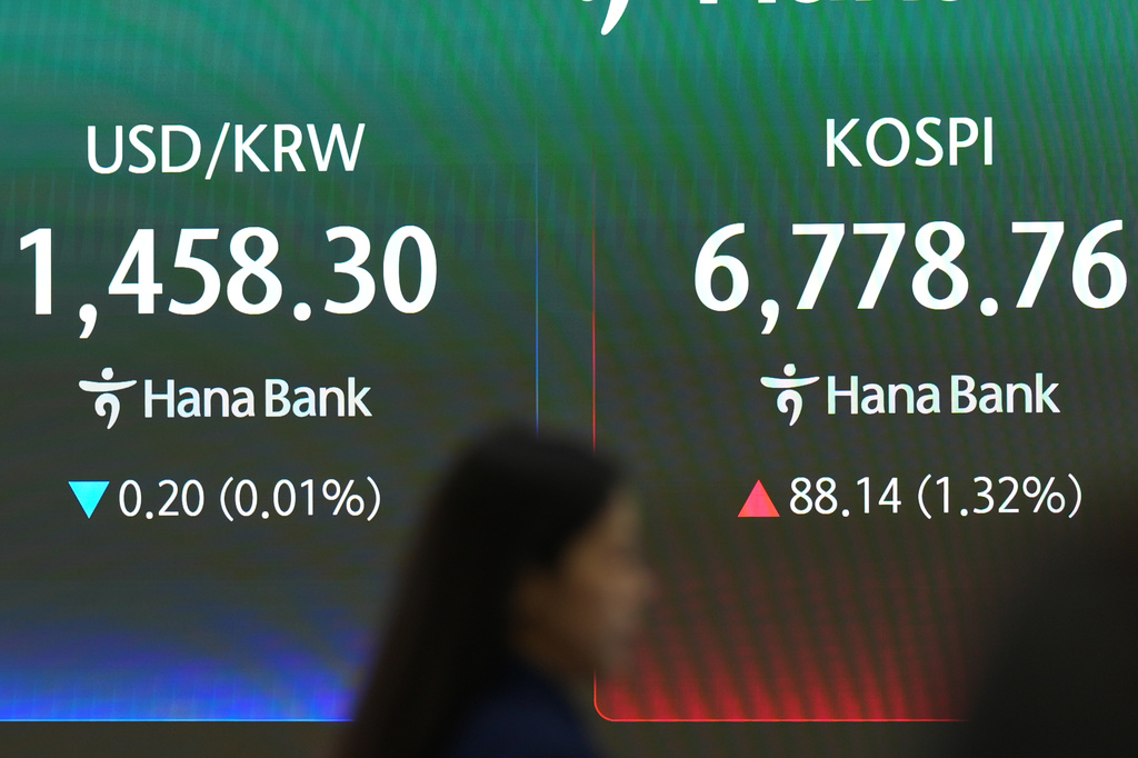 A dealer walks past near the screens showing the Korea Composite Stock Price Index (KOSPI) and the foreign exchange rate between U.S. dollar and South Korean won at a dealing room of Hana Bank in Seoul, South Korea, Monday, July 27, 2026. (AP Photo/Lee Jin-man)