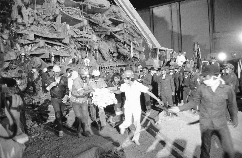 FILE - Emergency workers carry hospital patient Rubalcada Pena after rescuing him from the rubble of Mexico City's Juarez Hospital, which was destroyed by an earthquake, Sept. 26, 1985. (AP Photo/Jack Smith, File)