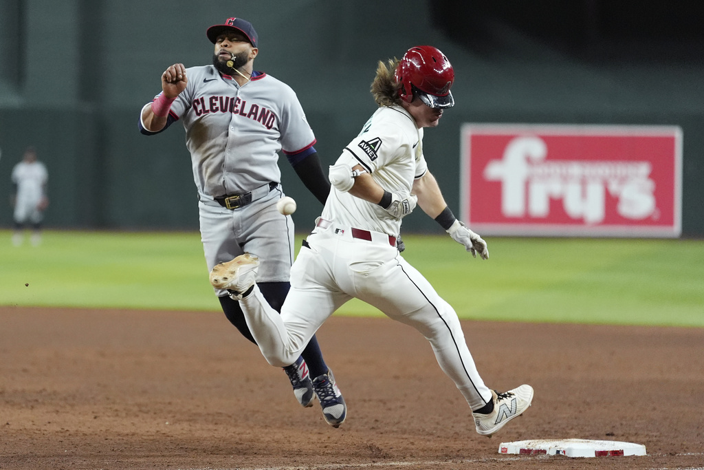 Arizona Diamondbacks' Jake McCarthy, right, runs out an infield single as Cleveland Guardians first baseman Carlos Santana, left, is unable to make a catch on a throwing error allowing Diamondbacks' McCarthy to advance to second base during the sixth inning of a baseball game Tuesday, Aug. 19, 2025, in Phoenix. (AP Photo/Ross D. Franklin)