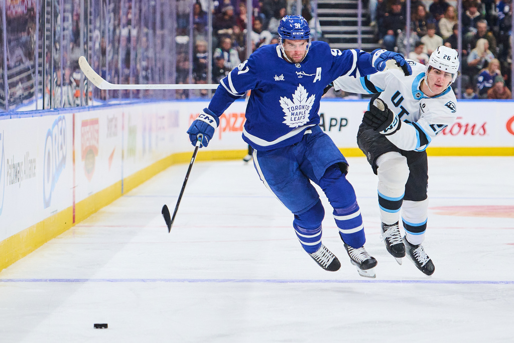 Toronto Maple Leafs' John Tavares (91) and Utah Mammoth's Dmitri Simashev (26) battle for the puck during second period NHL hockey action in Toronto, on Wednesday, Nov. 5, 2025. (Sammy Kogan/The Canadian Press via AP)