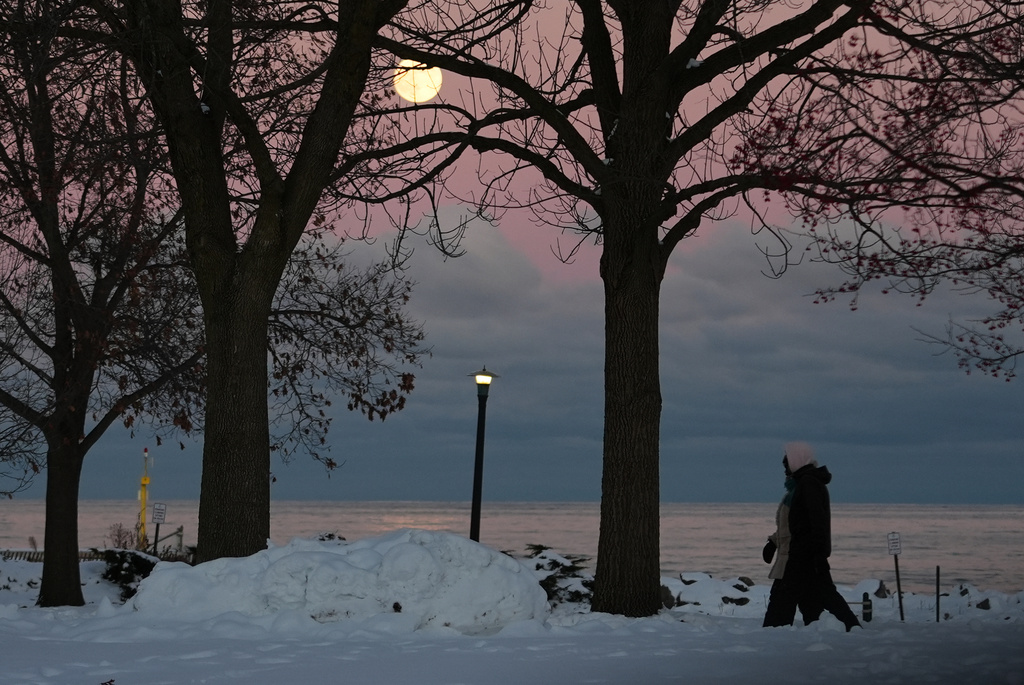 People bundle up as they take a walk during a cold weather day as the supermoon rises in Evanston, Ill., Thursday, Dec. 4, 2025. (AP Photo/Nam Y. Huh)