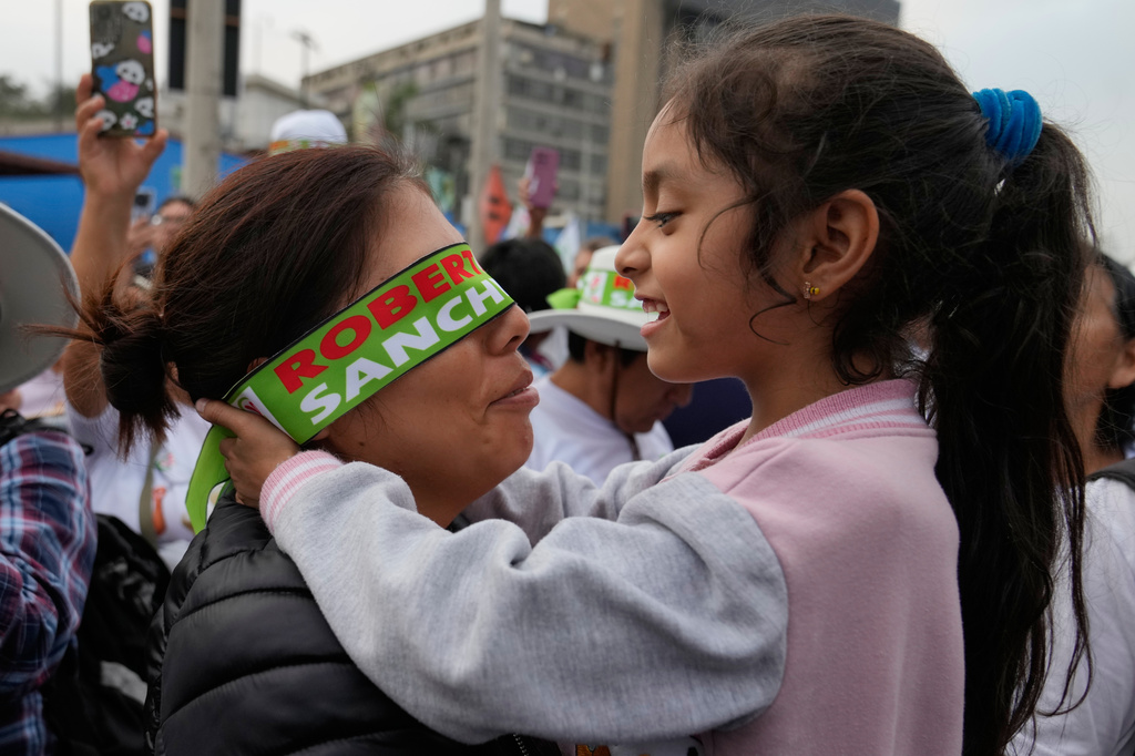 A girl embraces her mother during a campaign rally for presidential candidate Roberto Sanchez of the Together for Peru party in Lima, Peru, Thursday, June 4, 2026. (AP Photo/Martin Mejia)