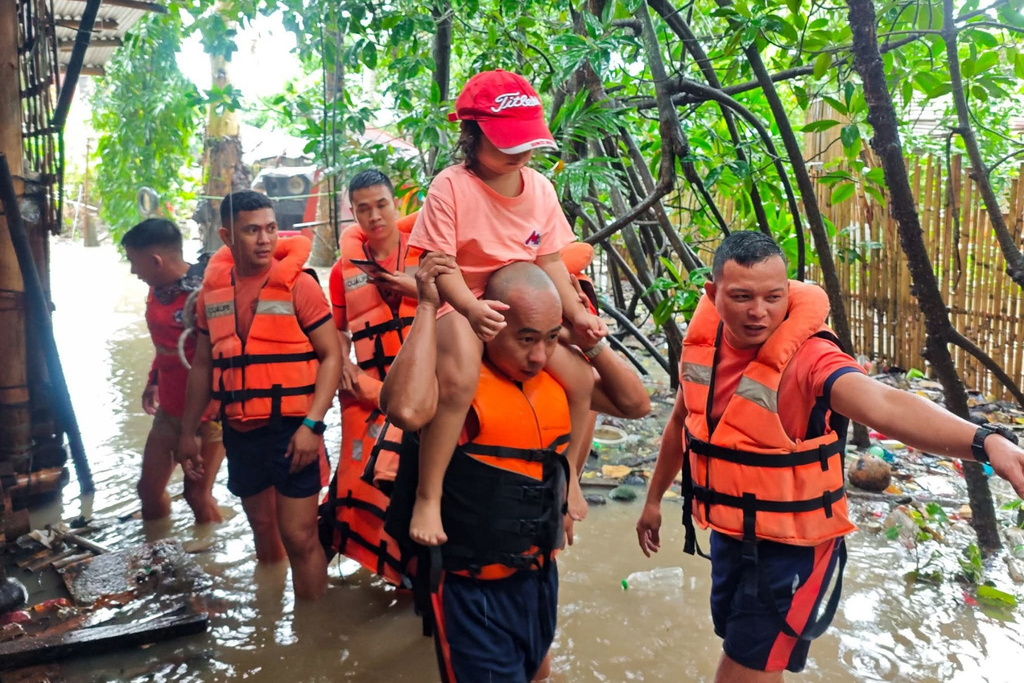 In this handout provided by the Philippine Coast Guard, rescuers move residents to safer grounds as floods rise due to Tropical Storm Bualoi in Bacolod city, Negros Occidental province, Philippines Friday, Sept. 26, 2025. (Philippine Coast Guard via AP)