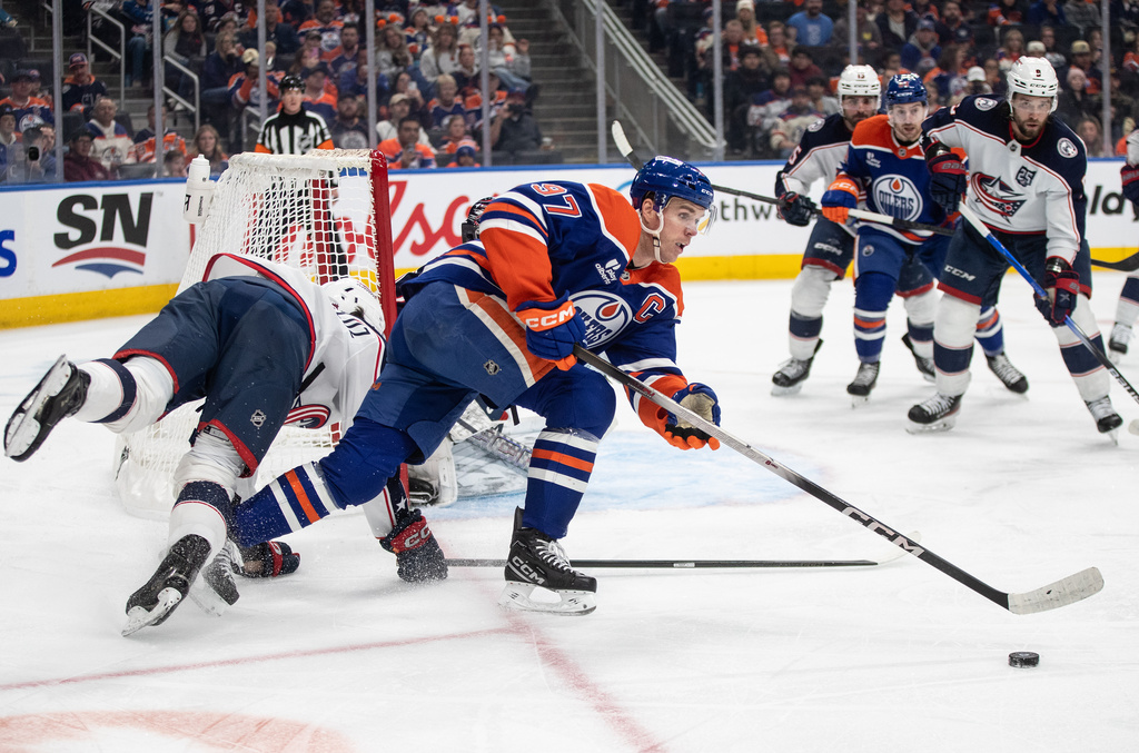 Columbus Blue Jackets' Luca Del Bel Belluz, left, hits the net while chasing Edmonton Oilers' Connor McDavid (97) during second-period NHL hockey game action in Edmonton, Alberta, Monday, Nov. 10, 2025. (Jason Franson/The Canadian Press via AP)