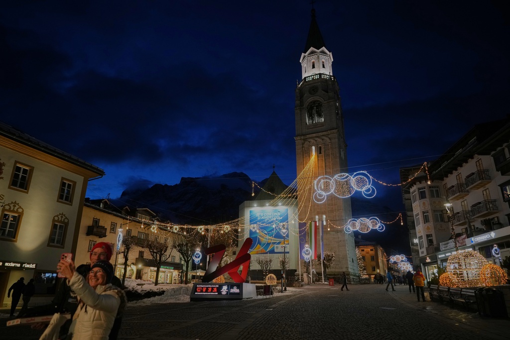 A couple takes a photo in front of the Milan Cortina Winter Olympics countdown clock, in Cortina D'Ampezzo, Friday, Nov. 21, 2025. (AP Photo/Andrew Medichini)