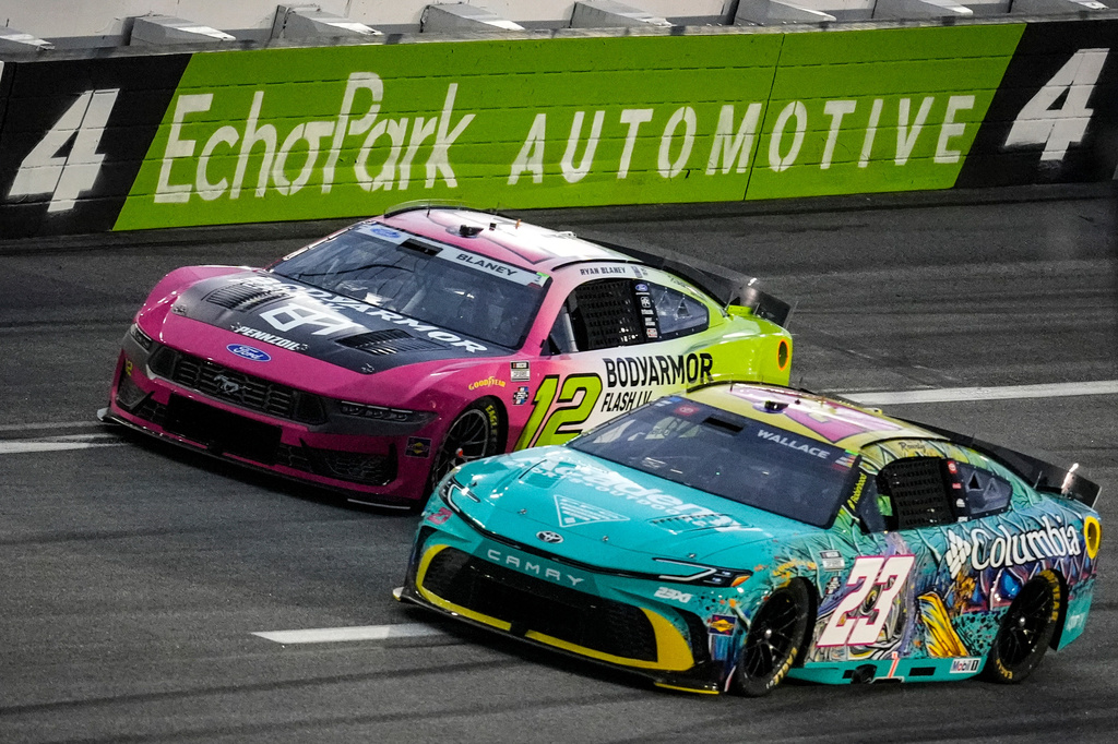 Bubba Wallace (23) and Ryan Blaney (12) move on the track during a NASCAR Cup Series auto race, Sunday, July 12, 2026, in Hampton, Ga. (AP Photo/Mike Stewart)