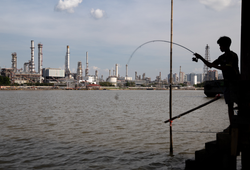 FILE - A boy fishes in front of the Bangchak Oil Refinery, home to Thailand's newest sustainable aviation fuel facility, in Bangkok on Jan. 3, 2026. (AP Photo/Anton L. Delgado, File)