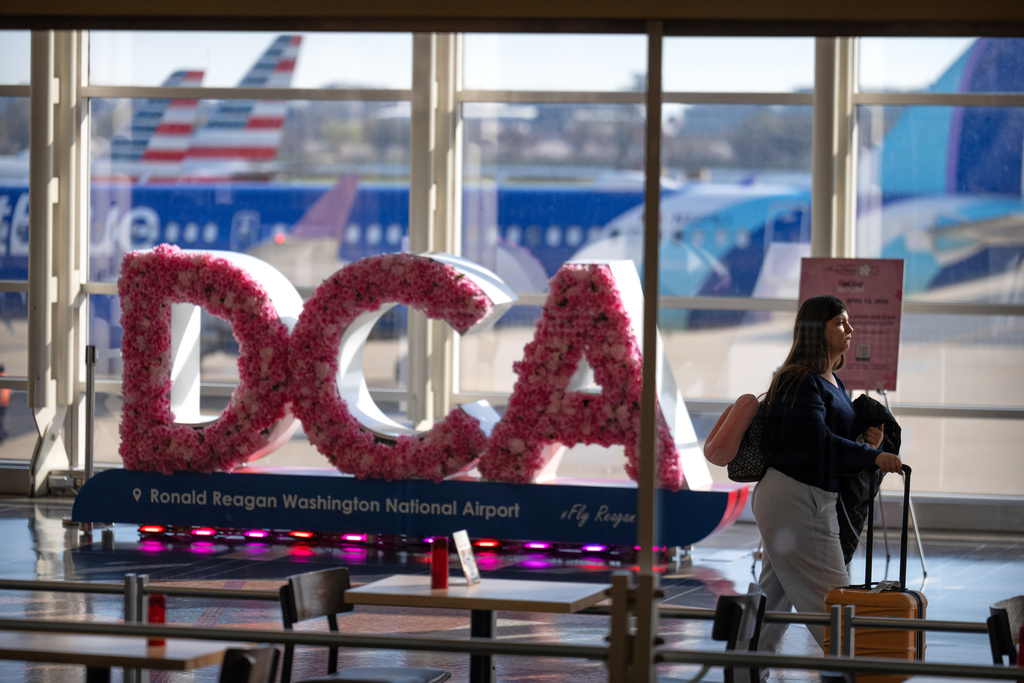 A traveler walks along the concourse at Reagan National Airport, Tuesday, March 24, 2026, in Washington. (AP Photo/Mark Schiefelbein)