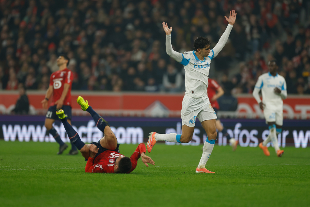 Lille's Olivier Giroud, bottom, lies on the pitch as Marseille's Nayef Aguerd reacts during the French League One soccer match between Lille and Marseille in Villeneuve-d'Ascq, outside Lille, France, Friday, Dec. 5, 2025. (AP Photo/Jean-Francois Badias)