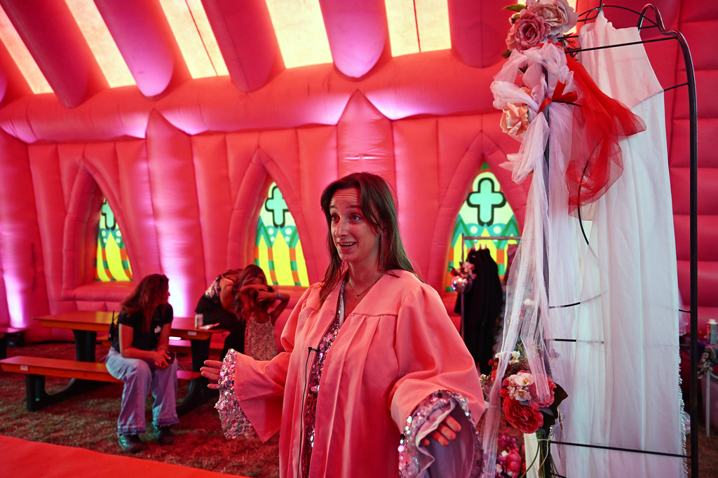 Julia van den Beek officiates during a mass wedding ceremony in an inflatable chapel in Amsterdam, Netherlands, Thursday, Aug. 6, 2026, as part of Pride events celebrating 25 years since the Netherlands became the first country in the world to legalize same-sex marriage. (AP Photo/Mouneb Taim)