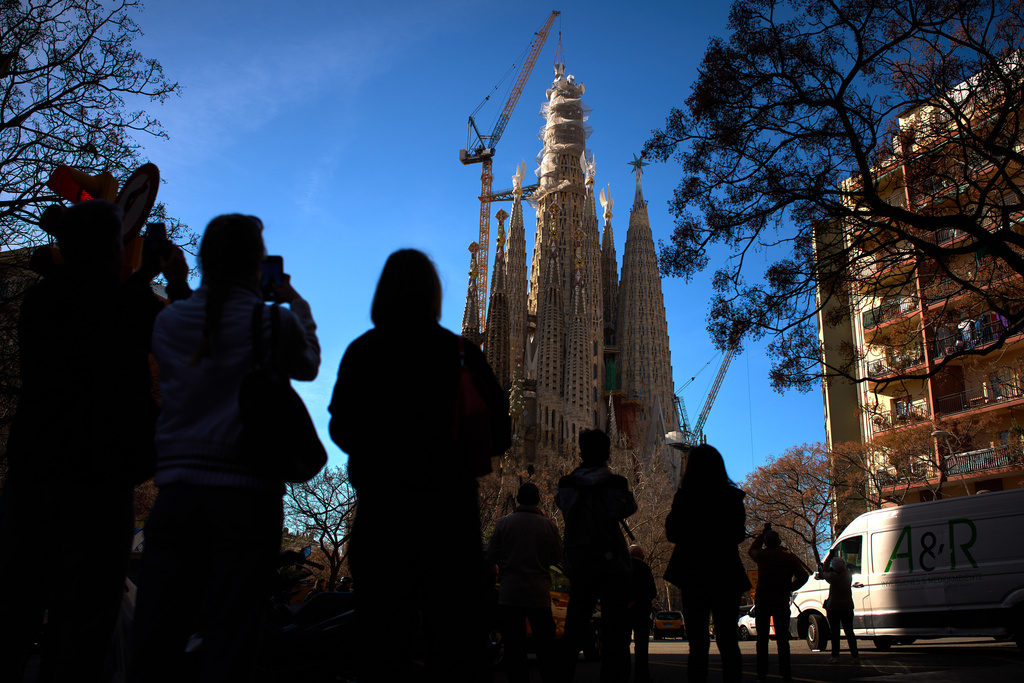 People watch as a crane lifts the upper arm of the cross onto the Tower of Jesus Christ at the Sagrada Familia in Barcelona, Spain, Friday, Feb. 20, 2026, reaching the basilica's maximum height of 172.5 meters (566 feet). (AP Photo/Emilio Morenatti)
