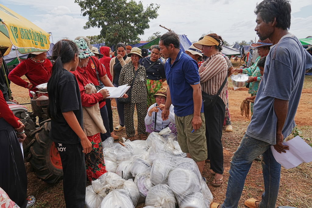 Evacuees wait for receiving a pot to cook rice as they take refuge at Chonkal in Oddar Meanchey province, Cambodia Thursday, Dec. 11, 2025, after fleeing homes following fighting between Thailand and Cambodia over territorial claims. (AP Photo/Heng Sinith)