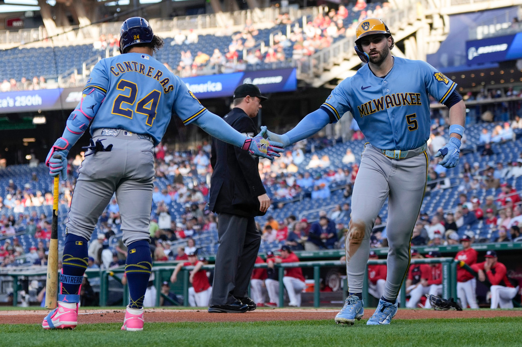 Milwaukee Brewers' Garrett Mitchell (5) celebrates with William Contreras (24) after scoring against the Washington Nationals on a passed ball during the first inning of a baseball game, Friday, May 1, 2026, in Washington. (AP Photo/Jess Rapfogel)