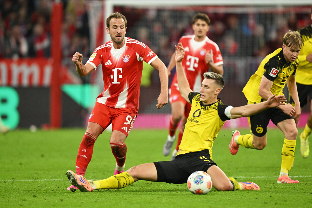 Bayern's Harry Kane, left, and Dortmund's Nico Schlotterbeck, centre, in action during the Bundesliga soccer match between Bayern Munich and Borussia Dortmund in Munich, Germany, Saturday, Oct. 18, 2025. (AP Photo/Lennart Preiss)