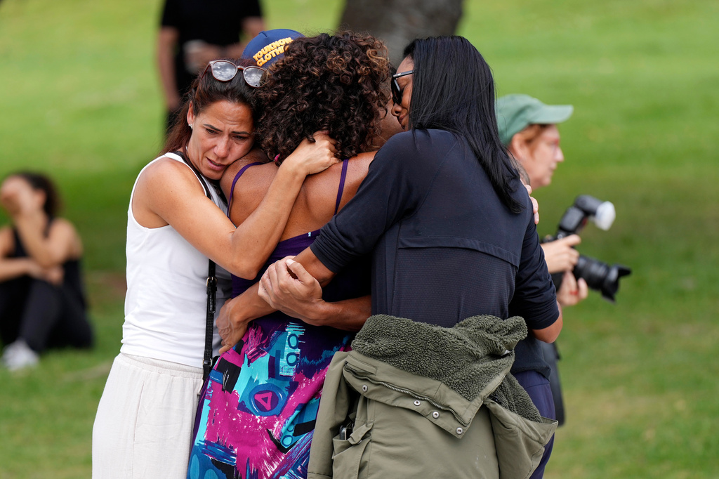 People offer hugs to each other at a flower memorial placed outside Bondi Pavilion at Sydney's Bondi Beach, Monday, Dec. 15, 2025, a day after a shooting. (AP Photo/Mark Baker)