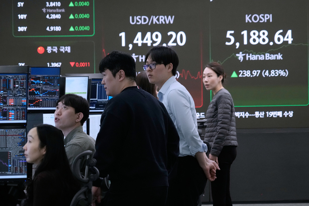 Currency traders watch monitors near a screen showing the Korea Composite Stock Price Index (KOSPI), right, and the foreign exchange rate between U.S. dollar and South Korean won at the foreign exchange dealing room of the Hana Bank headquarters in Seoul, South Korea, Tuesday, Feb. 3, 2026. (AP Photo/Ahn Young-joon)