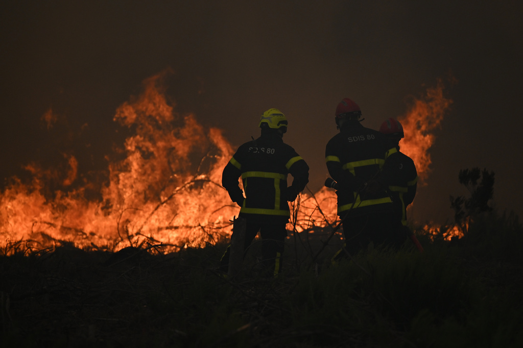 Firefighters spray water in a burning forest near Lacanau, southwestern France, Saturday, July 25, 2026. (AP Photo/Emma Da Silva)