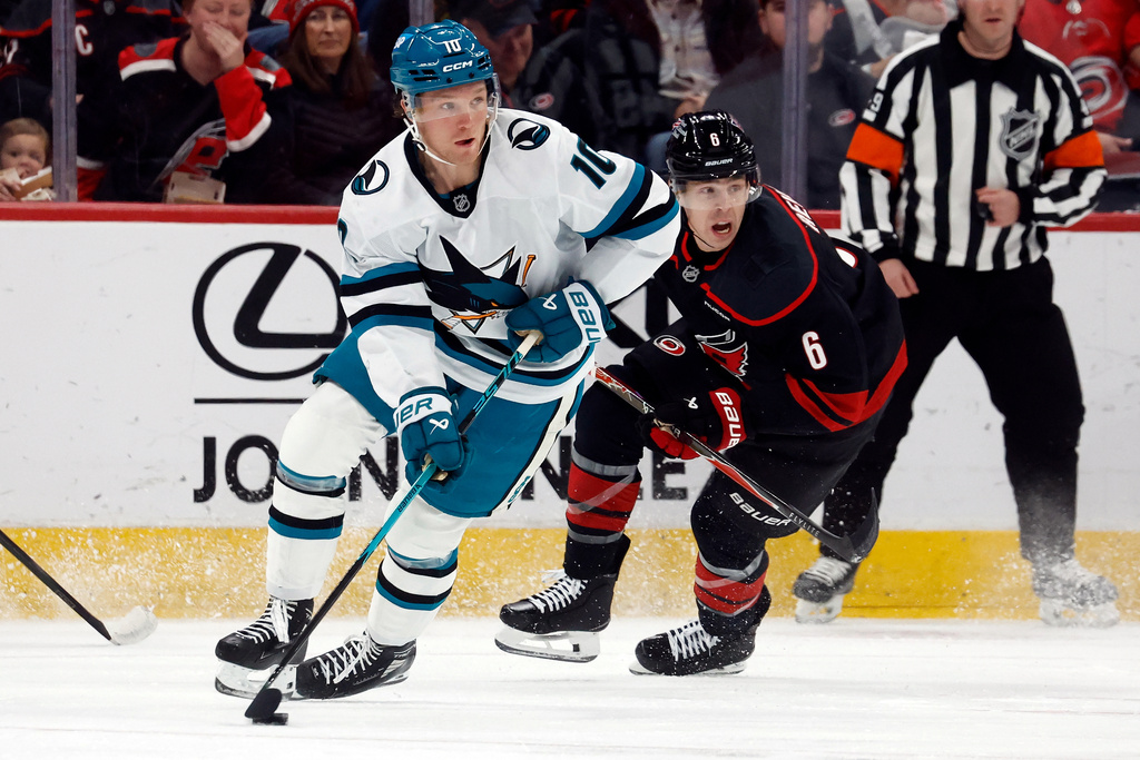 San Jose Sharks' Ty Dellandrea (10) controls the puck in front of Carolina Hurricanes' Mike Reilly (6) during the first period of an NHL hockey game in Raleigh, N.C., Sunday, Dec. 7, 2025. (AP Photo/Karl DeBlaker)