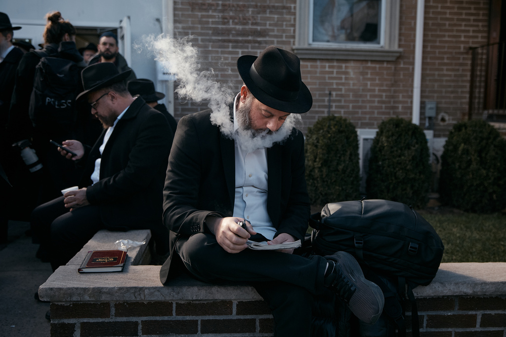 A Chabad-Lubavitch rabbi vapes as he prays near the resting place of the Rebbe, Rabbi Menachem M. Schneerson, one of Judaism’s most influential figures, in the Queens borough of New York on Friday, Nov. 14, 2025, during the International Conference of Chabad-Lubavitch Emissaries. (AP Photo/Andres Kudacki)