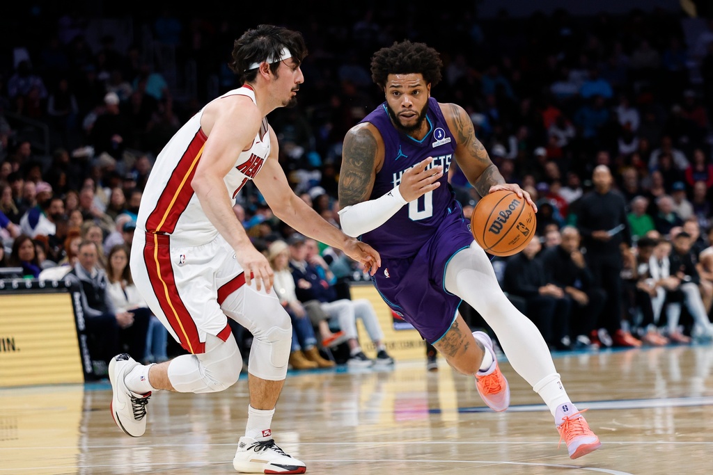 Charlotte Hornets forward Miles Bridges, right, drives to the basket against Miami Heat forward Jaime Jaquez Jr. during the first half of an NBA basketball game, Tuesday, March 17, 2026, in Charlotte, N.C. (AP Photo/Nell Redmond)