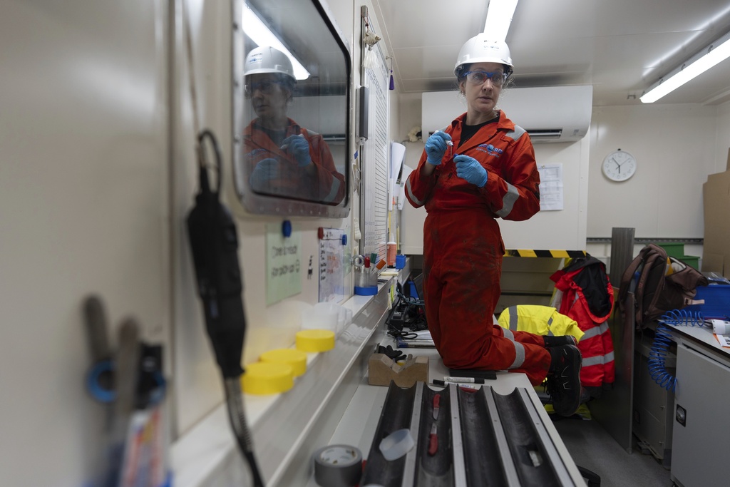 Expedition 501 researcher Patrizia Geprägs pauses as she writes current core data on a board in the curation container aboard the Liftboat Robert platform, in the North Atlantic, Sunday, July 20, 2025. (AP Photo/Carolyn Kaster)