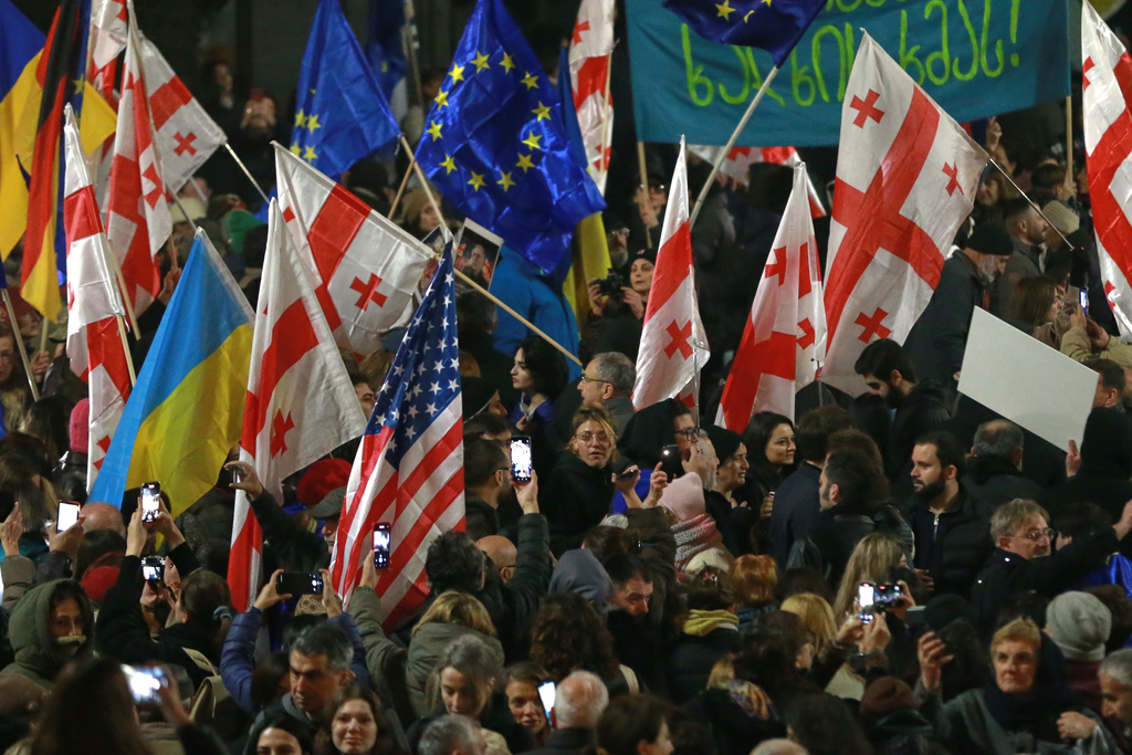Demonstrators with Georgian, Ukrainian, U.S. and EU flags gather in the Georgian capital of Tbilisi, on Friday, Nov. 28, 2025, to mark 365 days of non-stop protests against the government's decision to halt talks on joining the European Union. (AP Photo/Zurab Tsertsvadze)