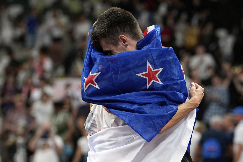 Gold medalist New Zealand's Hamish Kerr and silver medalist South Korea's Woo Sang-hyeok, background, embrace after the men's high jump final at the World Athletics Championships in Tokyo, Tuesday, Sept. 16, 2025. (AP Photo/Matthias Schrader)
