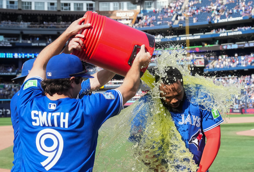 Toronto Blue Jays' Vladimir Guerrero Jr., right, is doused by Josh Smith (9) and Myles Straw, back left, after their team defeated the Baltimore Orioles in a baseball game in Toronto, Sunday, Sept. 13, 2026. (Nathan Denette/The Canadian Press via AP)