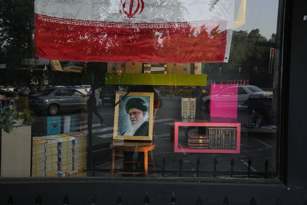 A portrait of slain Iranian Supreme Leader Ayatollah Ali Khamenei and an Iranian flag are displayed in the window of a book store ahead of Khamenei's funeral ceremonies, in Tehran, Iran, Thursday, July 2, 2026. (AP Photo/Vahid Salemi)